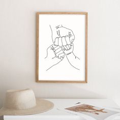 two hands are holding each other's fingers in black ink on white paper next to a hat