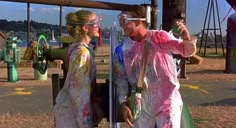 two people with goggles on standing next to each other in front of a playground