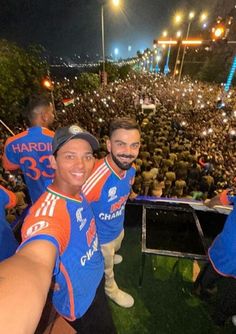 two men in blue and orange jerseys are taking pictures with their cell phones at an event