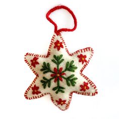 a christmas ornament hanging from a red string on a white background with green and red decorations