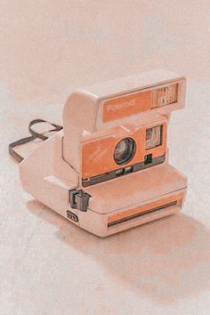 an orange and white polaroid camera sitting on top of a table next to a pair of scissors