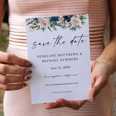 a person holding up a wedding save the date card with flowers on it in their hands