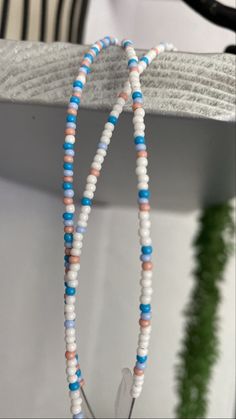 two strands of white and blue beads are hanging from a rack on a shelf next to a potted plant