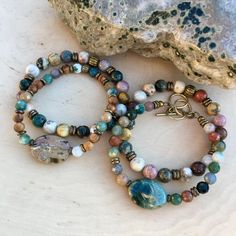 "I'm so happy to share these gorgeous Ocean Jasper stretch bracelets with you! I selected high quality 8mm round beads, and mixed them with rustic brass accent beads for a great look! You can easily mix these bracelets with your other favorites, or purchase more than one for a stacked look (as shown in the photos). You will receive one bracelet. Shown in size 7\", they also come is sizes 6\", 6.5\", 7.5\" and 8\". All are different, but equally beautiful. This multicolored natural stone from Mad Rustic Beaded Bracelets With Natural Stones, Rustic Multicolor Round Bead Bracelets, Stretch Beaded Bracelets, Carson City, Jasper Bracelet, Brass Accents, Ocean Jasper, Nature Bracelets, Stretch Bracelets