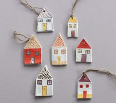 small ceramic houses are hanging from twine strings