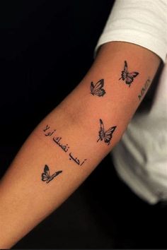 a woman's arm with three butterflies on it and the words, love is in arabic