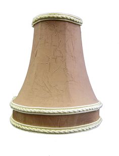 a brown and white lamp shade with rope trimmings on the bottom, against a white background