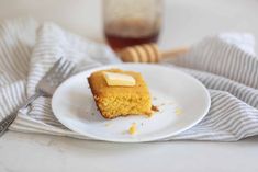 a piece of cake sitting on top of a white plate next to a jar of honey