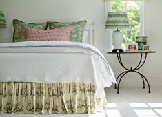 a white bed sitting in a bedroom next to a window with green lamps on top of it