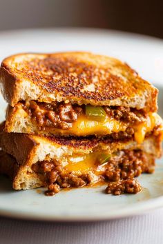 two grilled cheese sandwiches stacked on top of each other with chili and cheese in between