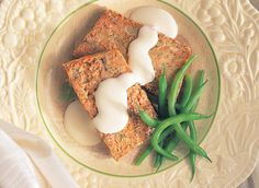 a white plate topped with food and green beans on top of a table next to a napkin