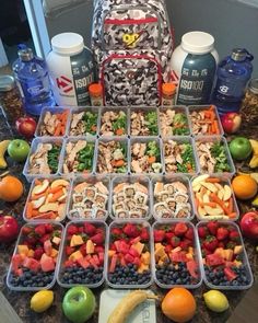 an assortment of fruits and vegetables in plastic containers on a table with a back pack