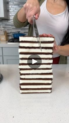 a woman cutting up a cake with a knife on top of it in the kitchen