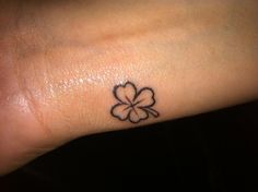 a small four leaf clover tattoo on the wrist