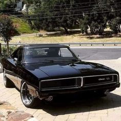 a black muscle car parked in front of a house