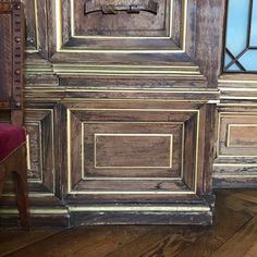 an old chair sitting in front of a wooden paneled wall with stained glass windows