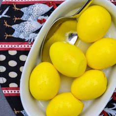 a white bowl filled with lemons on top of a black and white table cloth