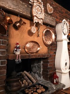 a fireplace with pots and pans hanging on the wall next to an old clock