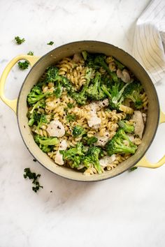 a pot filled with pasta and broccoli on top of a white countertop