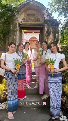 four women standing in front of a doorway holding flowers