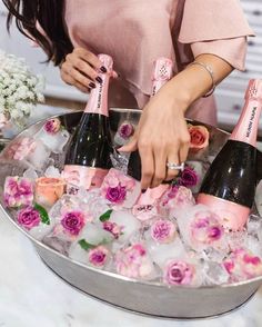 a woman in pink shirt pouring champagne into ice