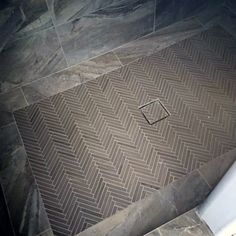 a bathroom with a tile floor that looks like chevron herringbones on the ground