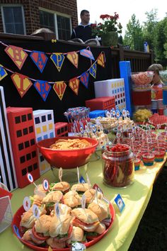 a table topped with sandwiches and drinks on top of a yellow tablecloth covered field