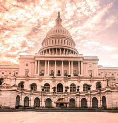 the capitol building in washington d c is pictured at sunset with pink clouds above it