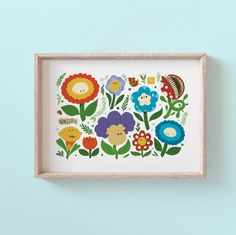 a wooden frame with colorful flowers and birds in it on a blue wall above a shelf