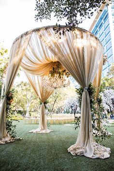 an outdoor wedding setup with drapes and flowers