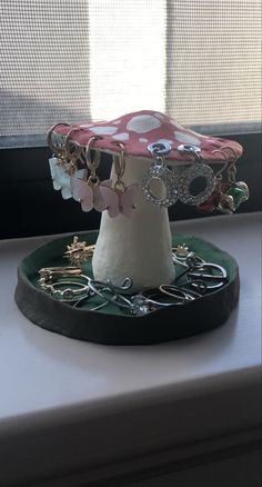 a mushroom shaped jewelry holder sitting on top of a window sill