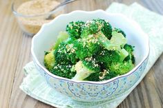 a bowl filled with broccoli on top of a wooden table