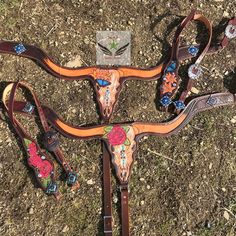 three different types of horse tacks with flowers on them, sitting in the grass