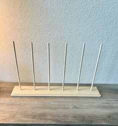 a wooden stand with four white sticks sticking out of it's sides on a wood table