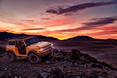 a yellow jeep parked on top of a rocky hill