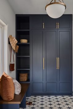 a room with blue cupboards and white tile flooring, including a wooden bench