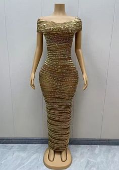 a mannequin wearing a gold dress on display in front of a white wall