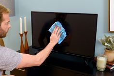 a man wiping his television screen with a blue cloth