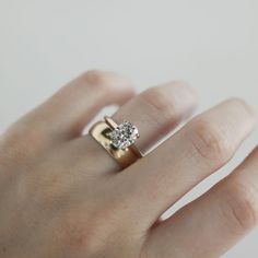 a woman's hand with a diamond ring on top of her finger, against a white background