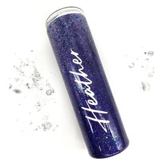 the purple glitter tumbler is next to some silver flakes and sparkles around it