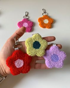 four crocheted flower keychains being held by a person's hand