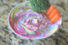 a bowl filled with dip, carrots and broccoli