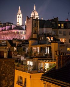 the city skyline is lit up at night, with buildings in the foreground and lights on