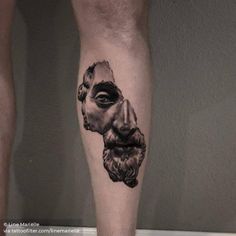 a man's leg with a black and white tattoo of an old man on it