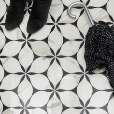 a black and white tiled floor with an umbrella on it's side, next to a pair of boots