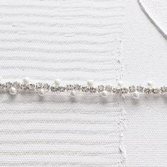 the beading is being sewn on to a piece of white fabric with pearls