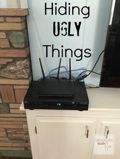 a tv sitting on top of a white cabinet next to a sign that says hiding ugly things