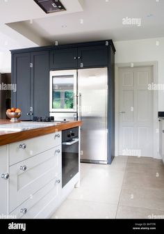 modern kitchen with stainless steel appliances and wood counter tops, white cabinets - stock image