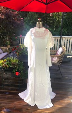 a white dress is displayed on a wooden deck with an umbrella in the foreground