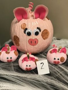 a pumpkin with pig faces on it next to three pigs and a sign that says 2